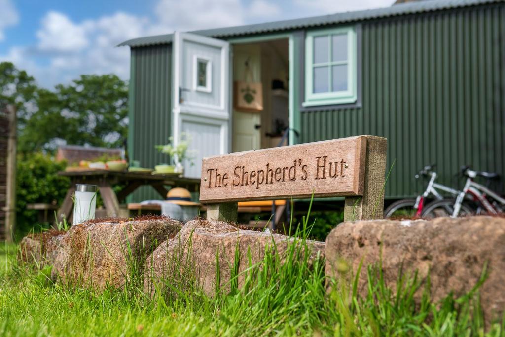 un cartel sentado en el césped frente a una casa en Romantic Shepherds Hut, Kenilworth, en Kenilworth