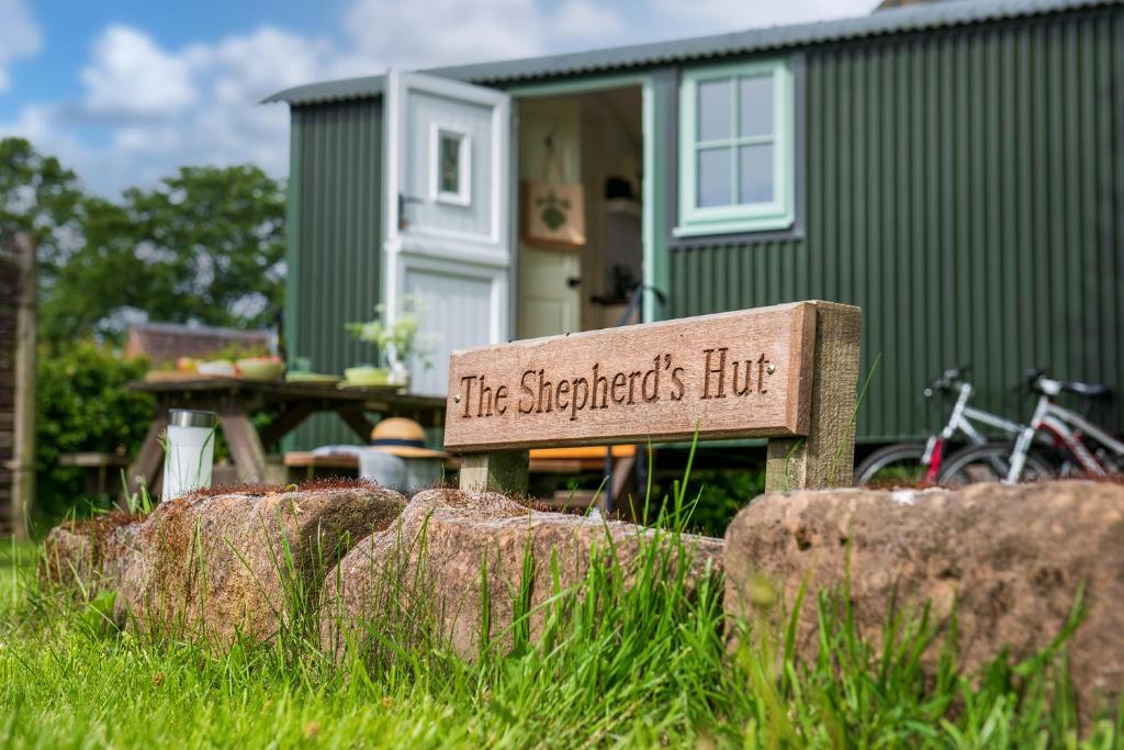 a sign sitting in the grass in front of a house at Romantic Shepherds Hut, Kenilworth in Kenilworth
