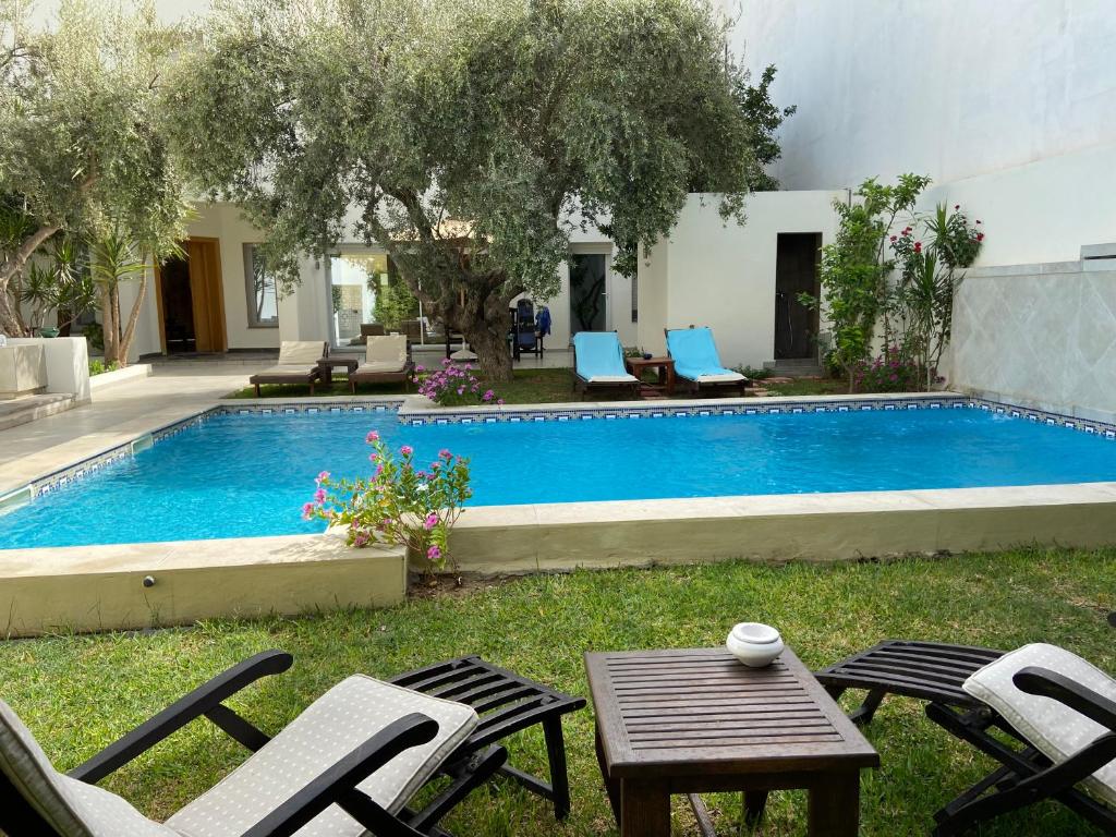 a swimming pool with chairs and a table next to it at Dar Misk la Marsa in La Soukra