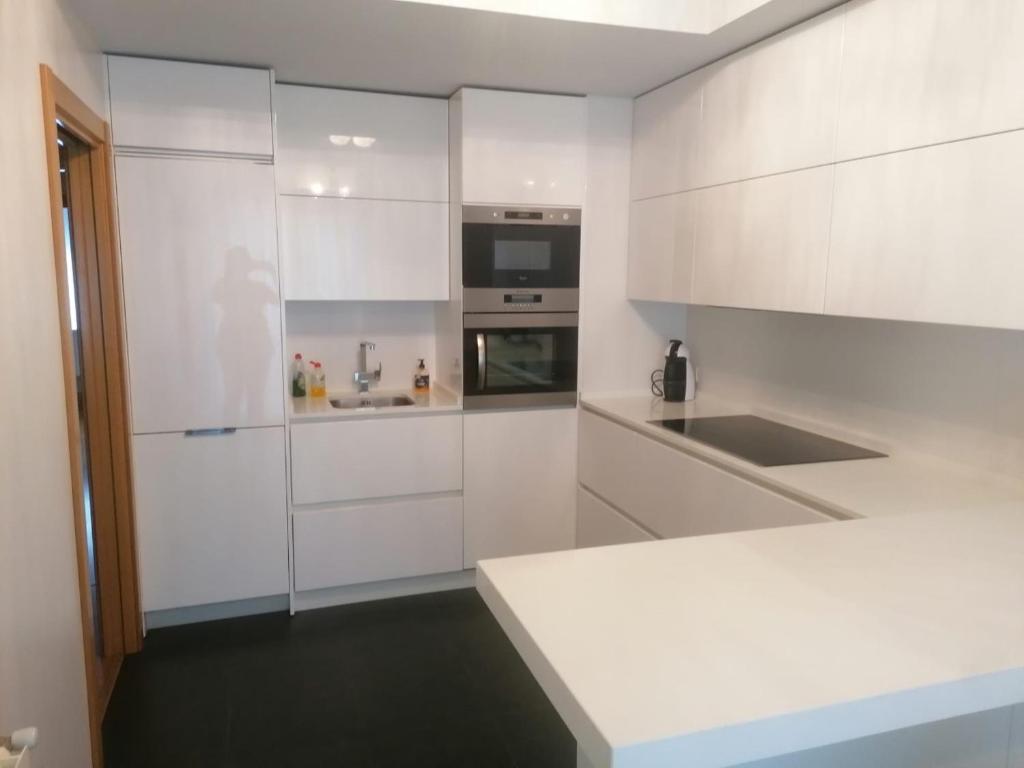 una cucina bianca con armadi bianchi e lavandino di Apartamento Praga a Vitoria-Gasteiz