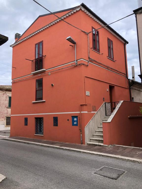 un edificio naranja con escaleras al lado de una calle en Casa Vico Torre, en Santa Croce di Magliano