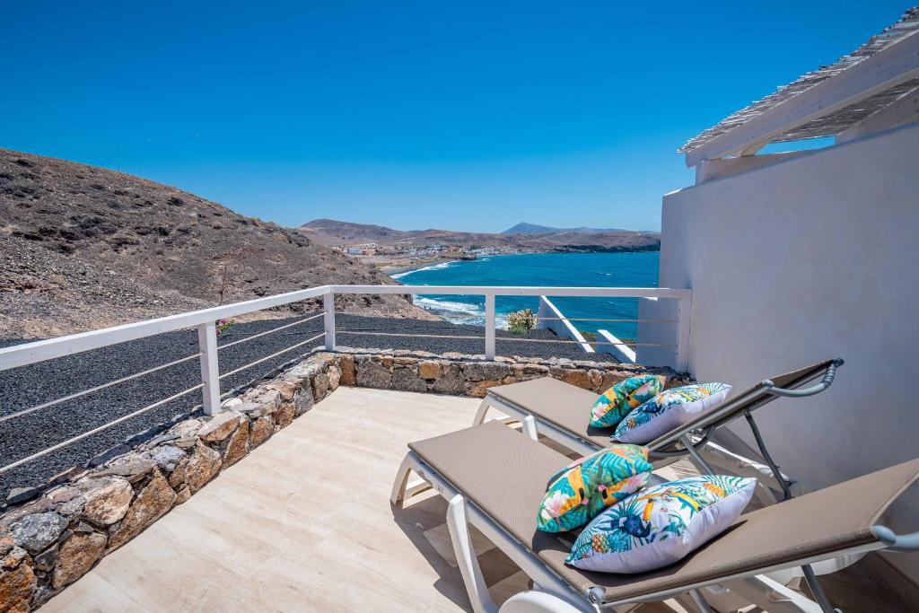 einen Balkon mit Stühlen und Blick auf das Wasser in der Unterkunft Etti Paradise Suite Mediterraneo in Pájara