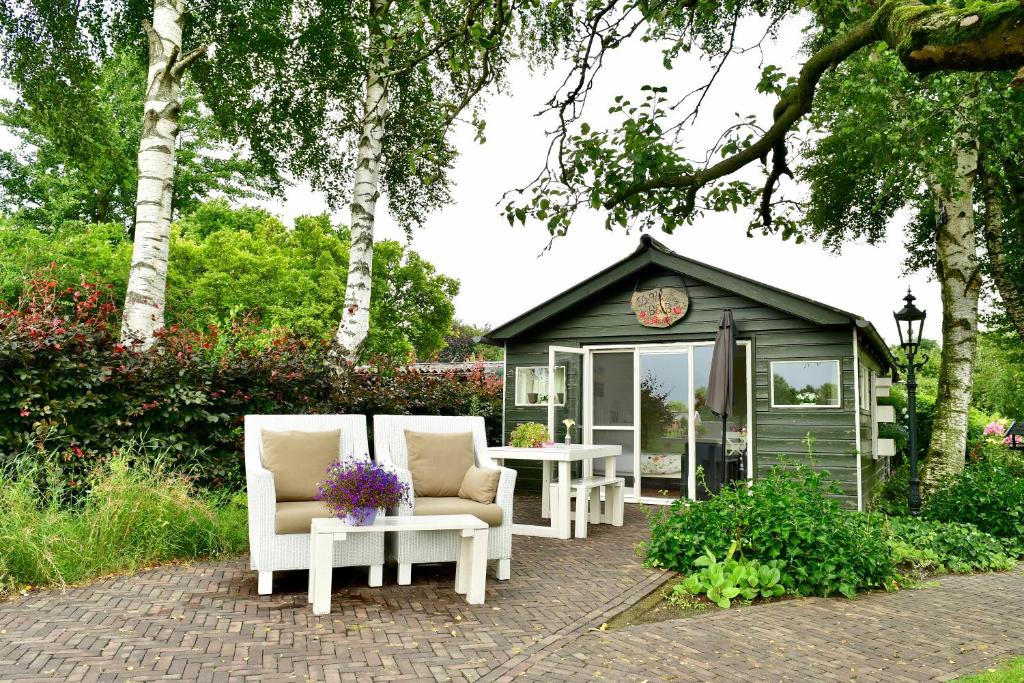 un cenador con sillas y una mesa frente a él en De Veldeling, en Hollandscheveld