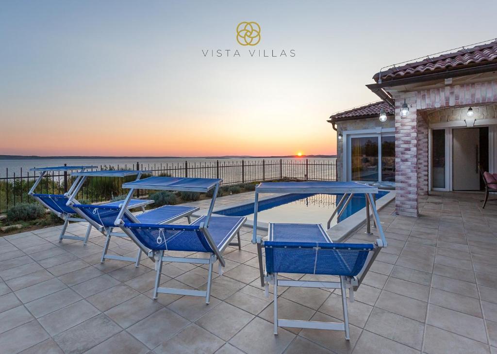 een groep blauwe stoelen en tafels op een patio bij Vista Villas - Sweet Life Apartment Villa S in Ražanac