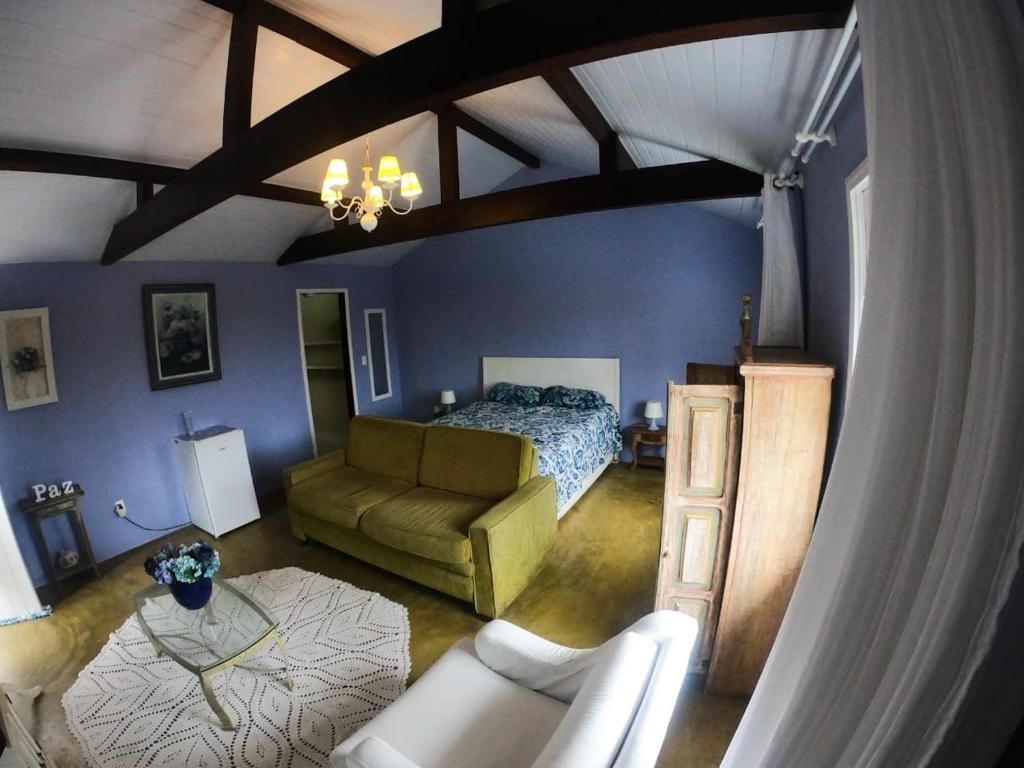 a bedroom with a bed and a couch at Loft Aconchego da Serra in Petrópolis