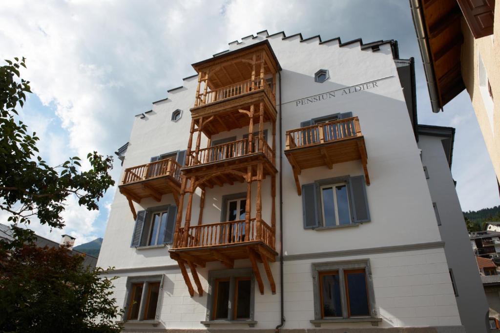 a white building with wooden balconies on it at Pensiun Aldier in Sent