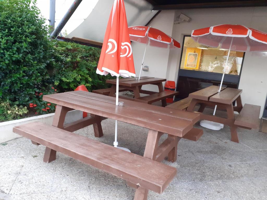 Duas mesas de piquenique com guarda-chuvas por cima. em hotelF1 Saintes em Saintes