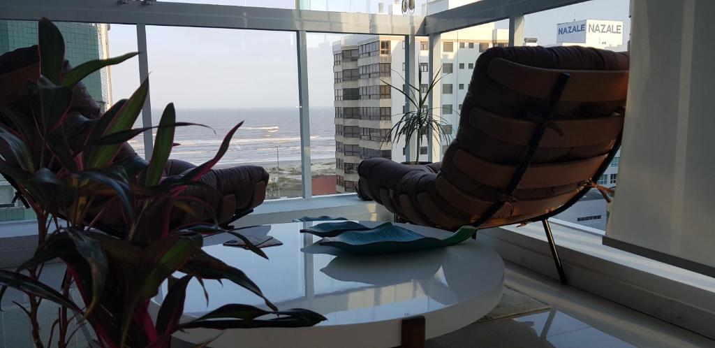 a living room with a table and chairs and a window at Em Capao da Canoa - Luxo e conforto com praia , sol e mar em Capão. in Capão da Canoa
