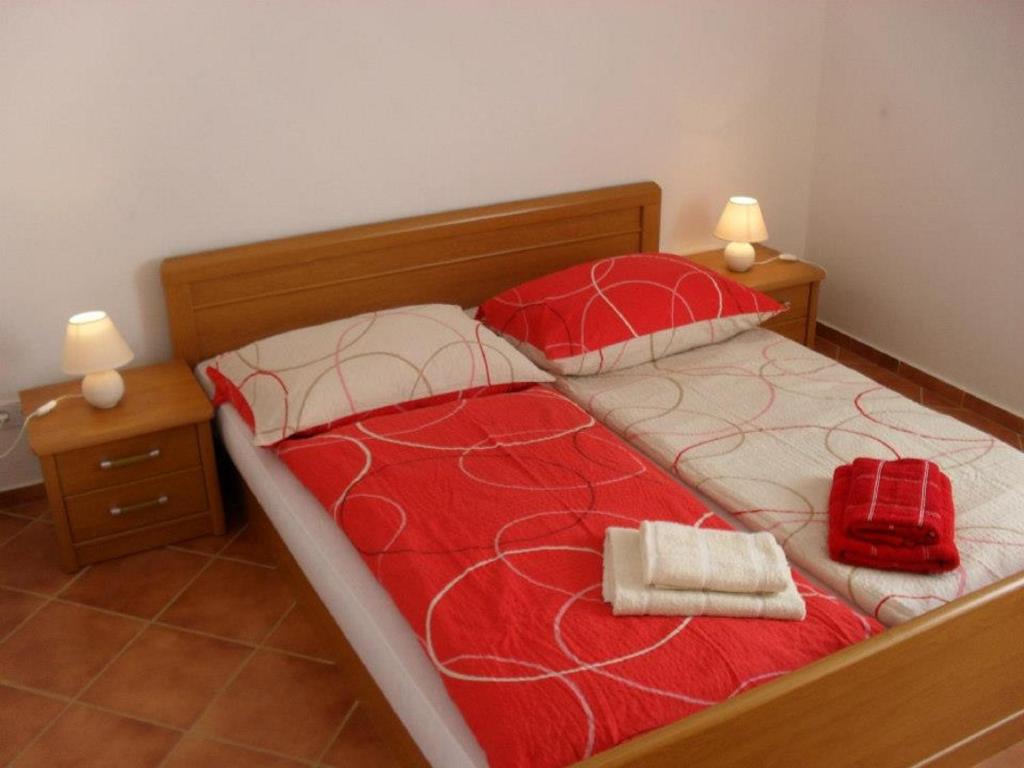 Una cama con dos almohadas y una bolsa roja. en Apartments Miljak en Fažana