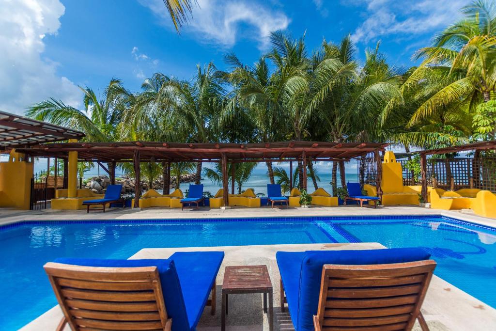 een zwembad met stoelen en palmbomen bij Hotel Meson de Mita in Punta Mita