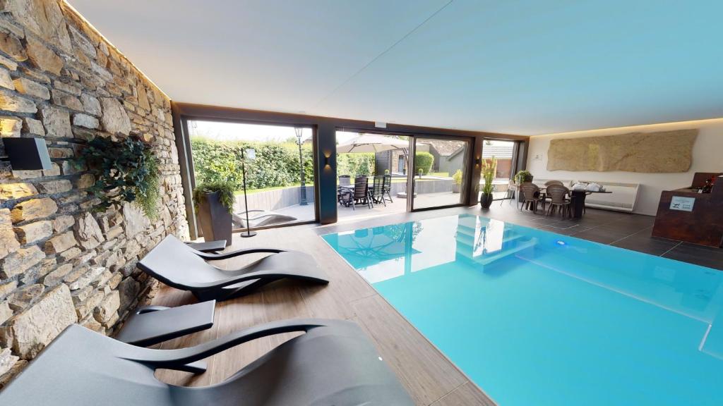 a house with a swimming pool and a stone wall at Ferienhof A&B Wellness Villa 12 personen in Bullange