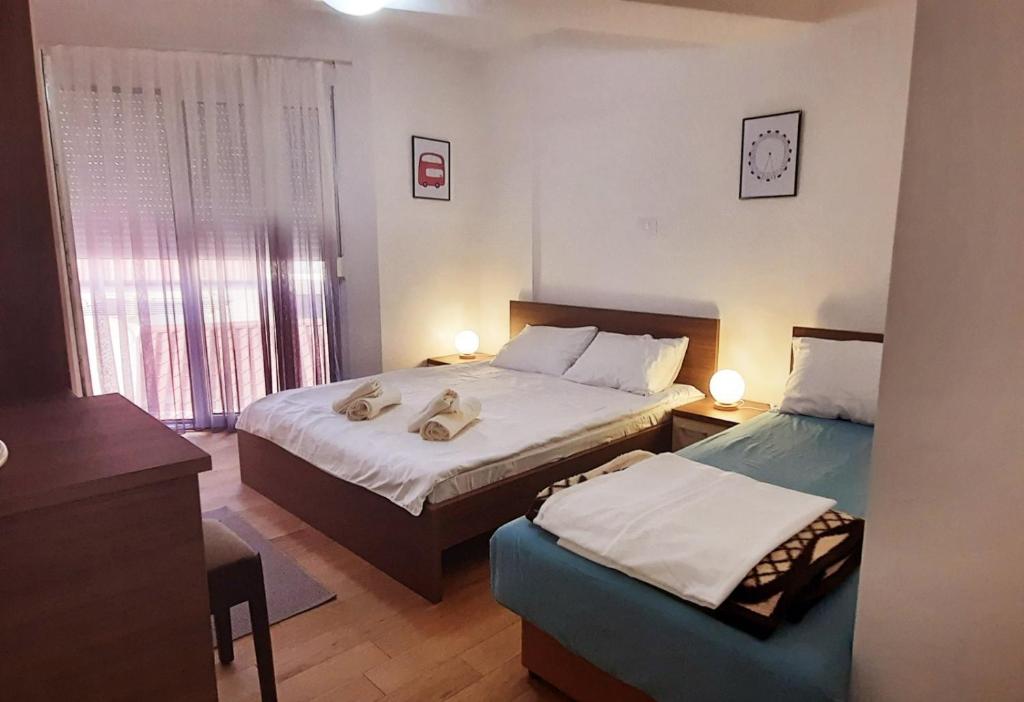 een slaapkamer met twee bedden, een bureau en een raam bij LYNX Apartments in Ohrid
