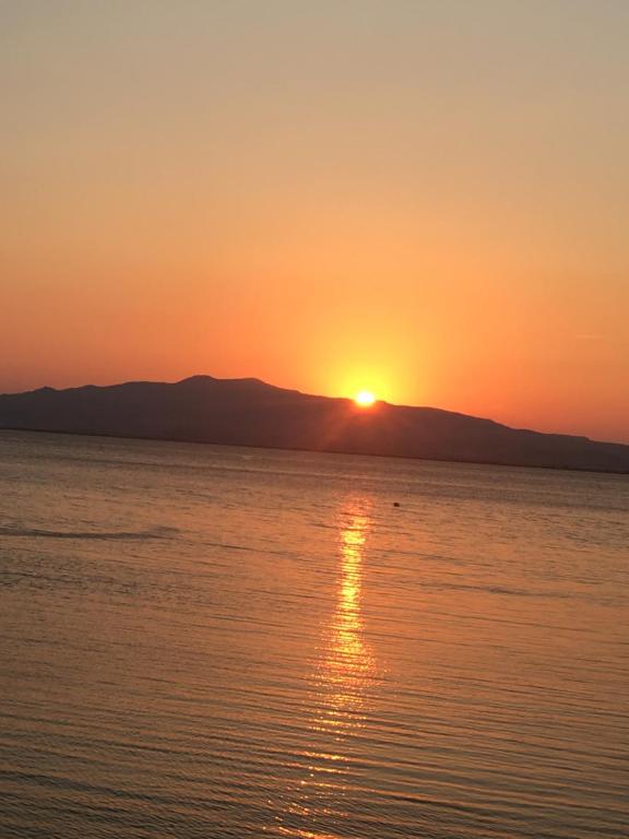 un coucher de soleil sur l'eau avec des montagnes en arrière-plan dans l'établissement Çandarlı little sweet house, à Dikili