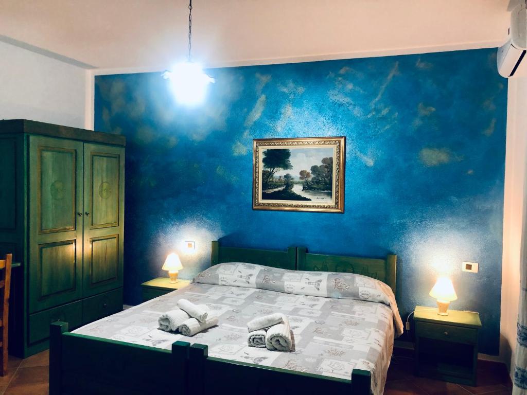 a bedroom with a bed with a blue wall at Arena Bianca in La Caletta