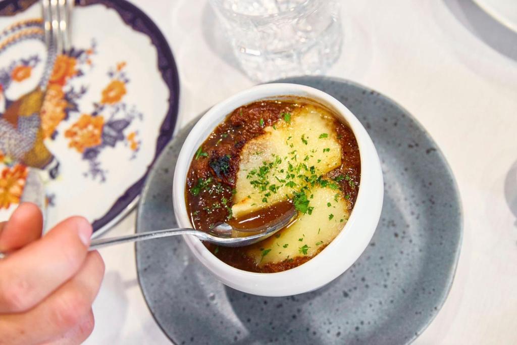 a person eating a bowl of soup with a spoon at Hotel Le Soleil by Executive Hotels in Vancouver