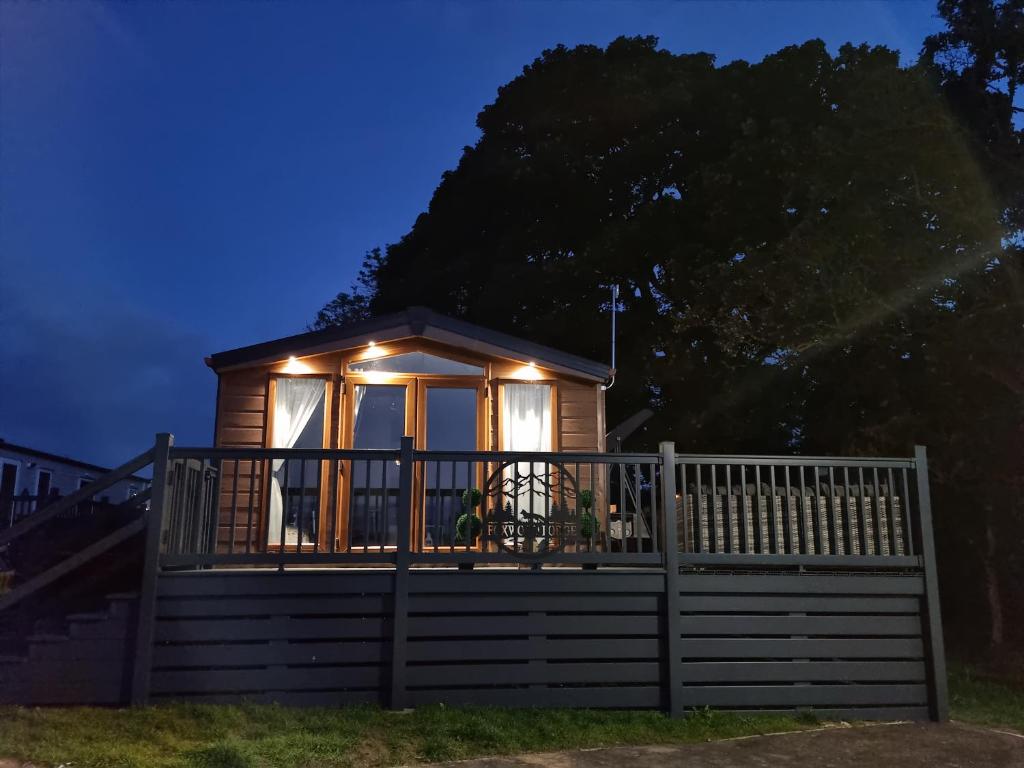 a tiny house with lights on the deck at night at Foxwood Lodge Private Hot Tub Getaway in Swarland