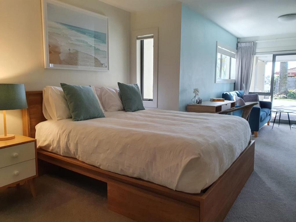 a bedroom with a large bed and a living room at Peaceful Mount Studio Moments to Beach & Downtown in Mount Maunganui