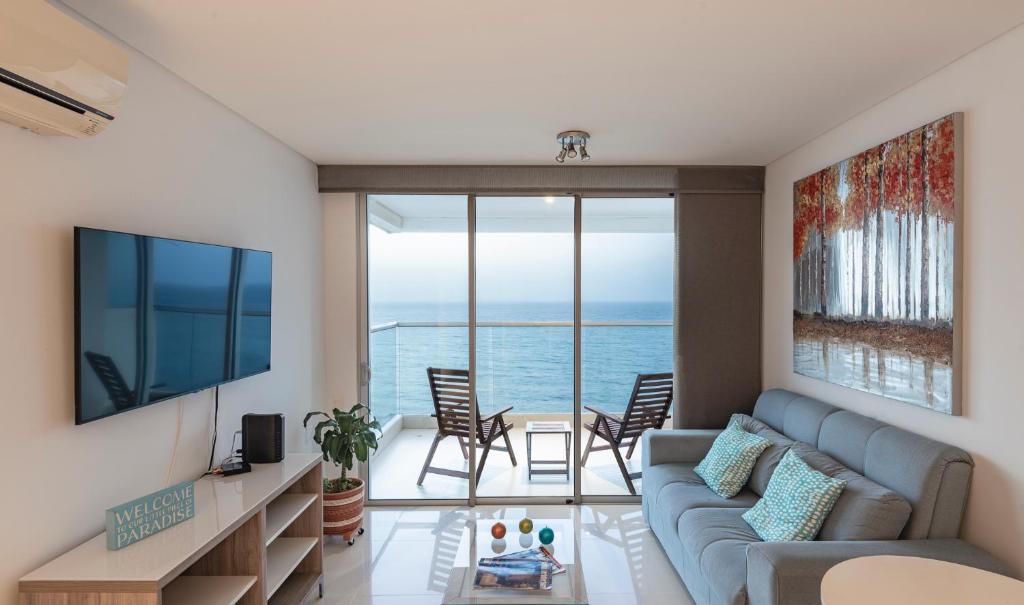 a living room with a couch and a view of the ocean at Relaxing 1 BR Beachfront Apartment w Wifi and Pool in Cartagena de Indias