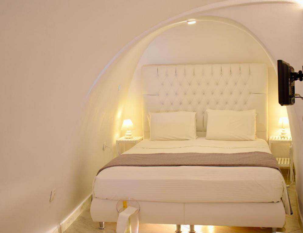 a white bed in a white bedroom with an archway at Aeolos Art & Eco Suites Adults Only in Imerovigli
