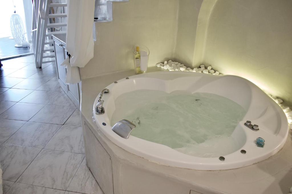 a large bath tub in a white bathroom with at Aeolos Art & Eco Suites Adults Only in Imerovigli