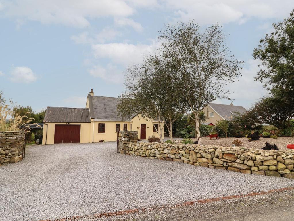 a house with a stone wall and a driveway at Silver Birch in Cuar an Chláir