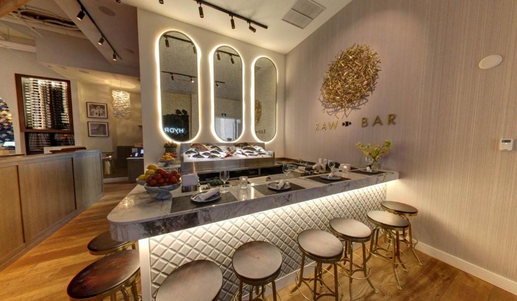 a bar with stools and a counter with a sink at EXchange Hotel Vancouver in Vancouver