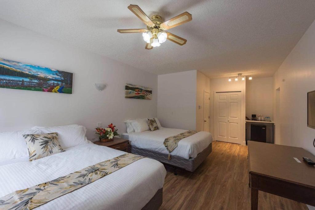 um quarto de hotel com 2 camas e uma ventoinha de tecto em David Thompson Resort em Cline River