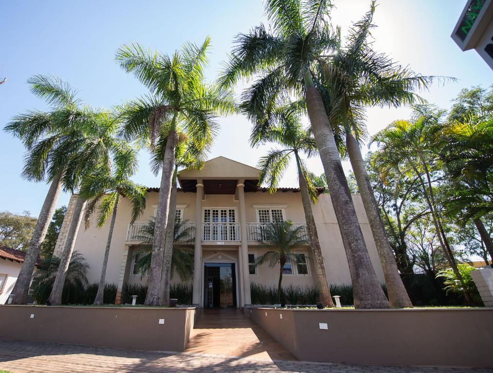 a building with palm trees in front of it at Nav Park Hotel in Naviraí