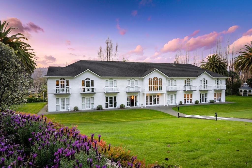 a large white house with a yard with flowers at Wallaceville Motor Lodge in Upper Hutt