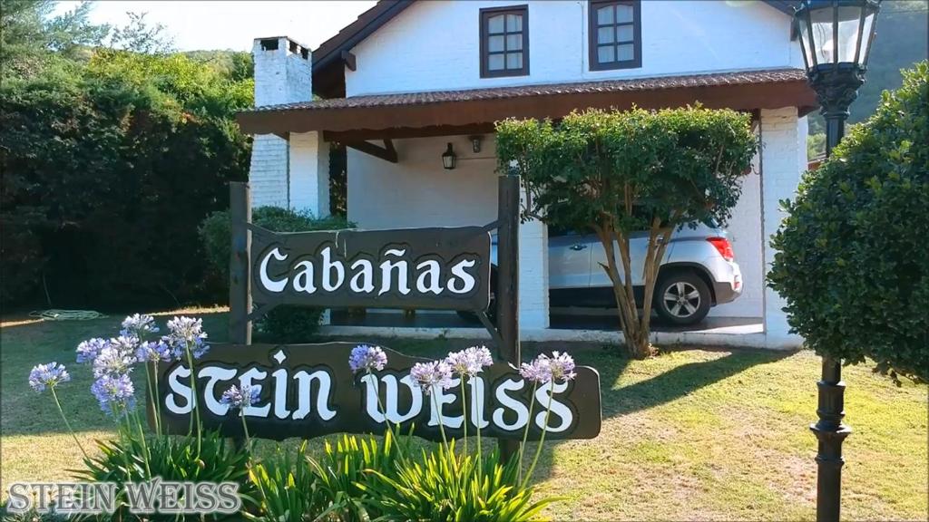 una señal frente a una casa blanca en Cabañas Stein Weiss en Santa Rosa de Calamuchita