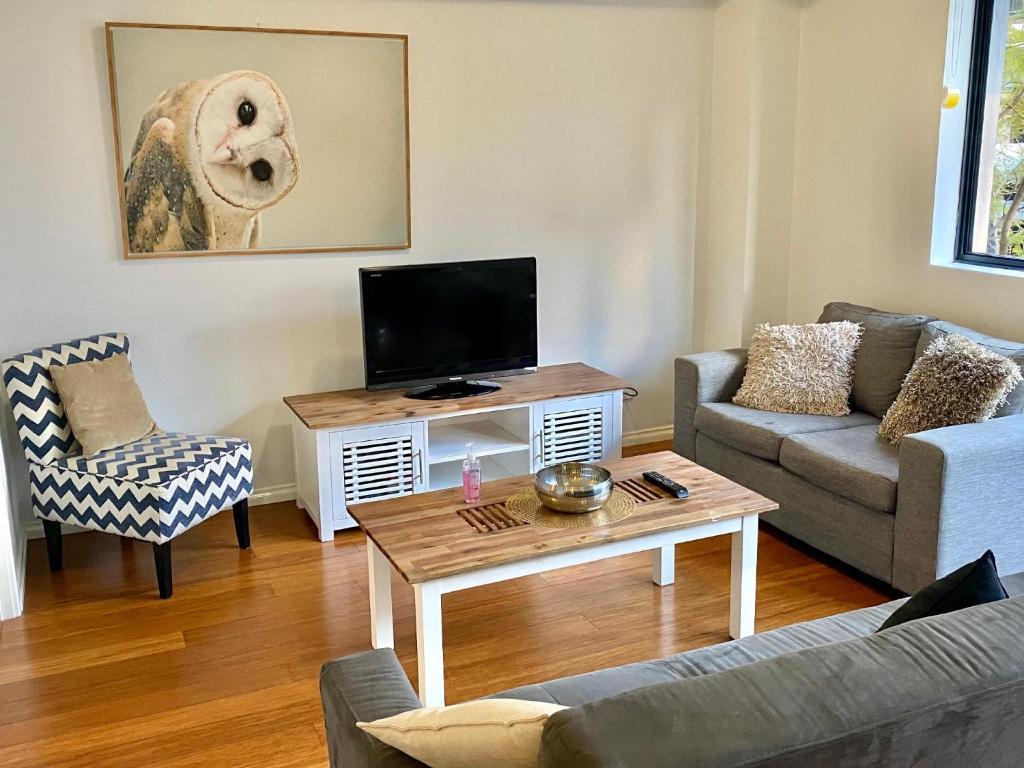 ein Wohnzimmer mit einem Sofa und einem TV in der Unterkunft 6 Executive Eastside Parking in Perth