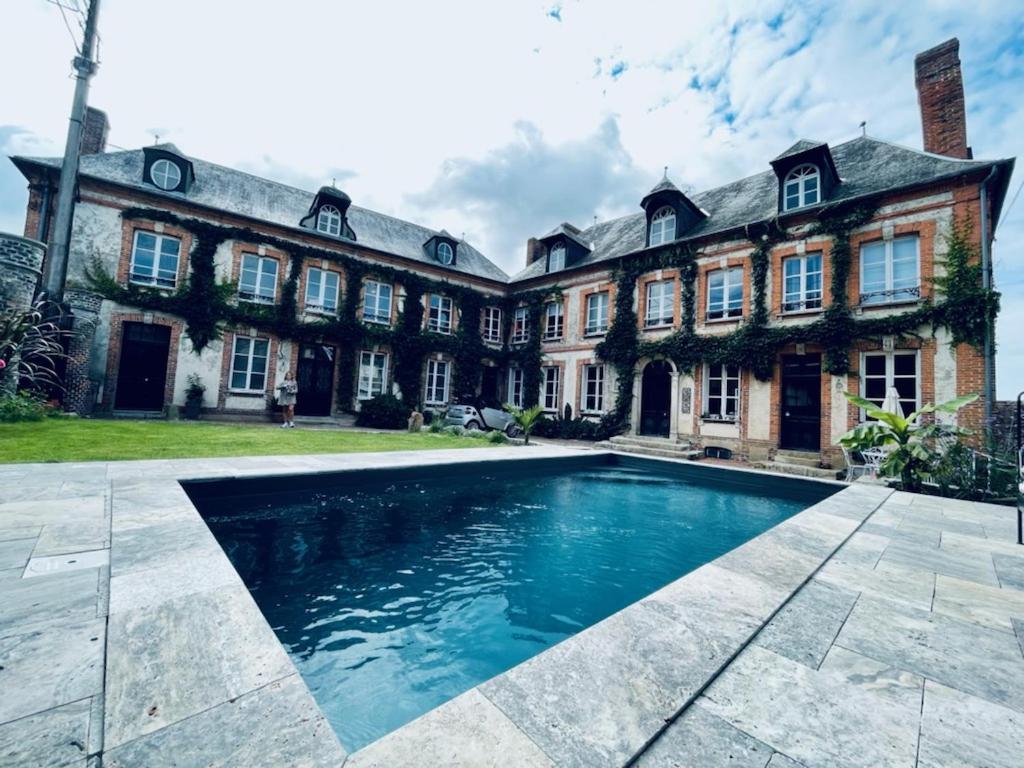 uma casa grande com uma piscina em frente em Maison d'hôtes l'Évidence em Rugles