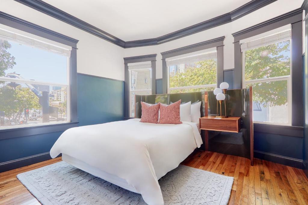 a bedroom with a large bed with blue walls and windows at Sonder The Baker in San Diego
