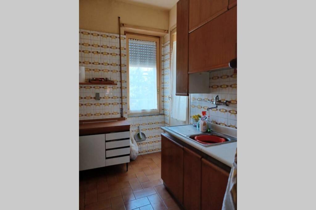 een keuken met houten kasten, een wastafel en een raam bij appartamento in centro Cassino in Cassino