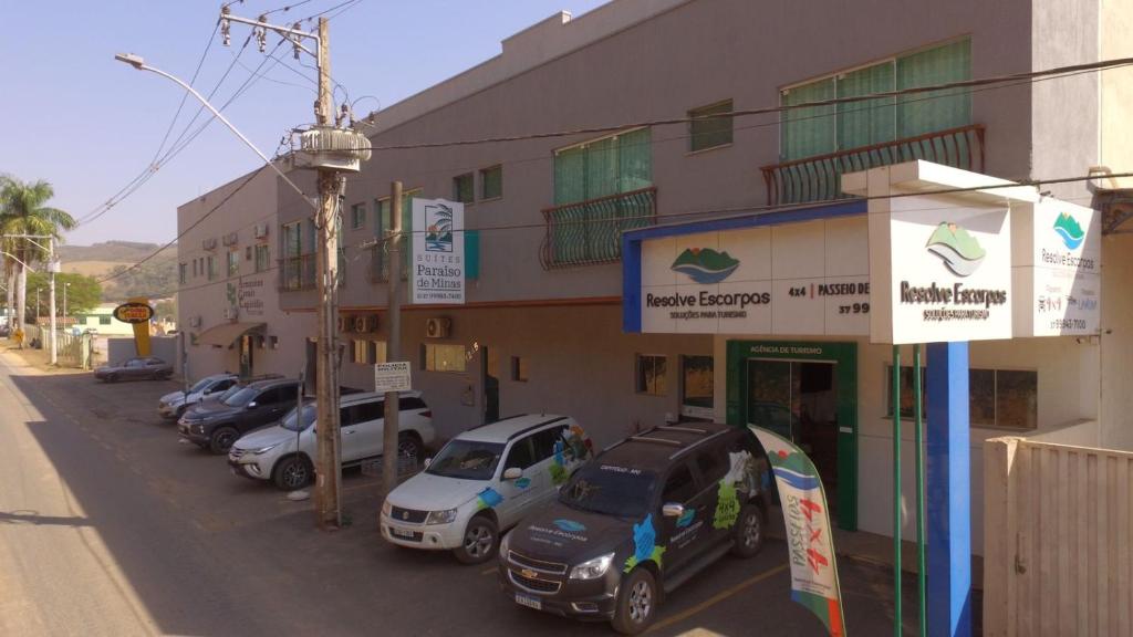 una fila di auto parcheggiate di fronte a un edificio di Suites Paraíso de Minas a Capitólio