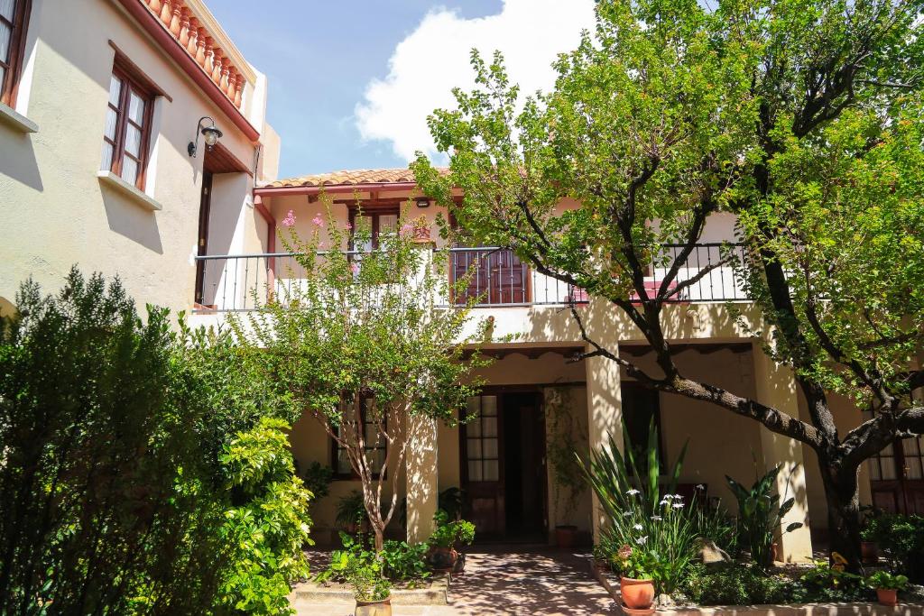 una casa con balcón y árboles frente a ella en Hotel Boutique La Posada, en Sucre