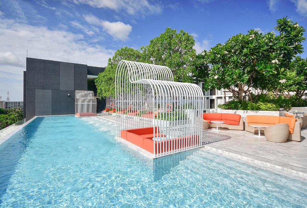 uma piscina com uma cerca branca ao lado de um edifício em dusitD2 Hua Hin em Hua Hin
