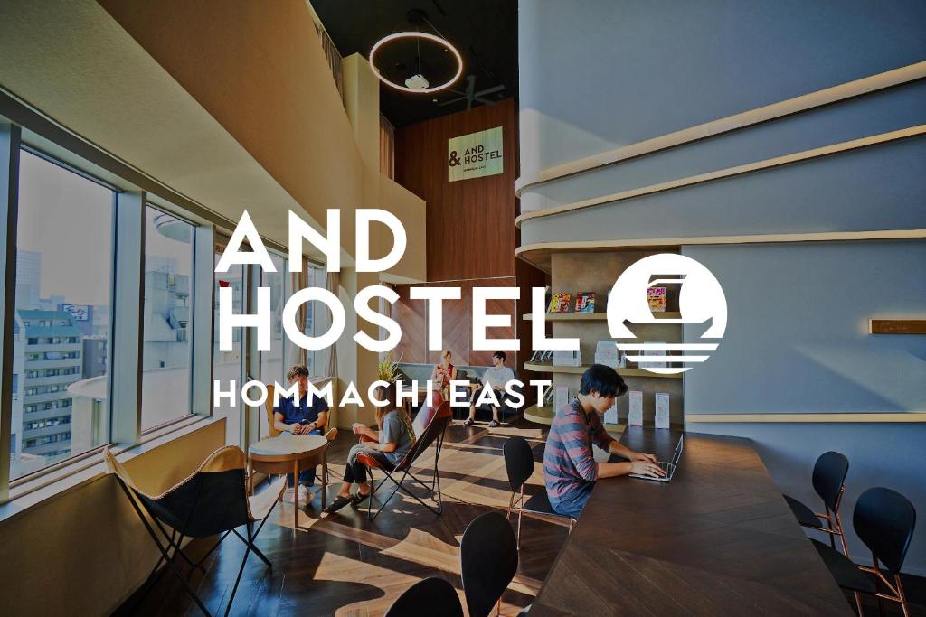 a room filled with tables and chairs filled with people at &AND HOSTEL HOMMACHI EAST in Osaka