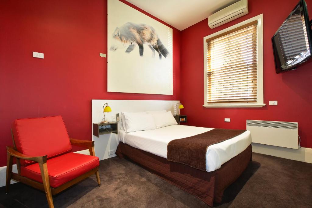 a red bedroom with a bed and a red chair at Tolarno Hotel in Melbourne