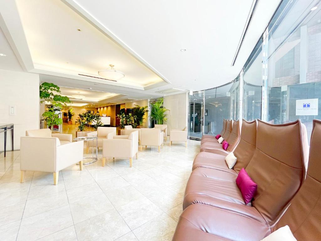 vestíbulo con sofá de cuero, mesas y sillas en Mars Garden Hotel Hakata en Fukuoka