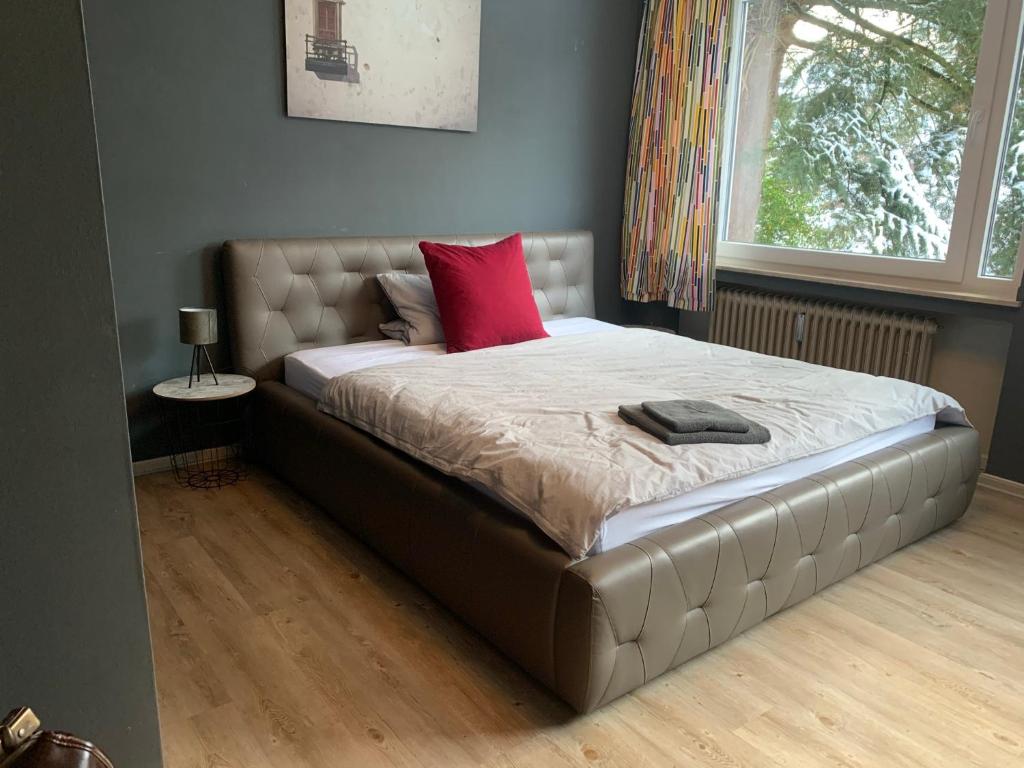 Una cama con una almohada roja encima. en Villa Hortensie, en Aachen