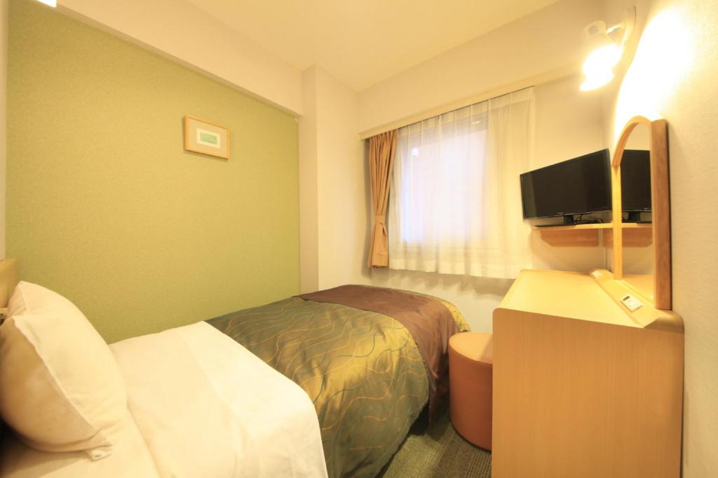 a hotel room with a bed and a desk and a television at Hotel Grand City in Tokyo