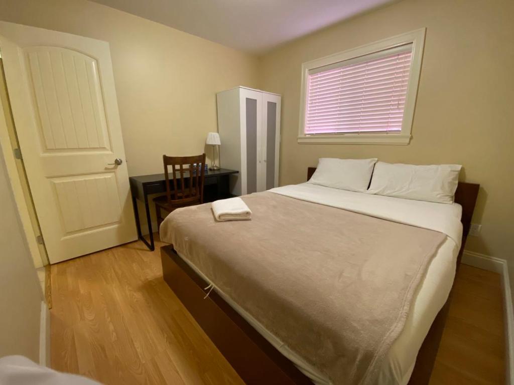 a bedroom with a bed and a table and a window at Victory House in Burnaby