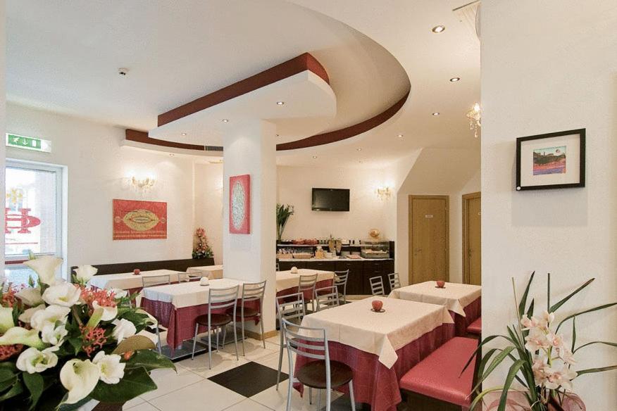 restauracja z białymi stołami, krzesłami i kwiatami w obiekcie Hotel Granducato w mieście Montelupo Fiorentino