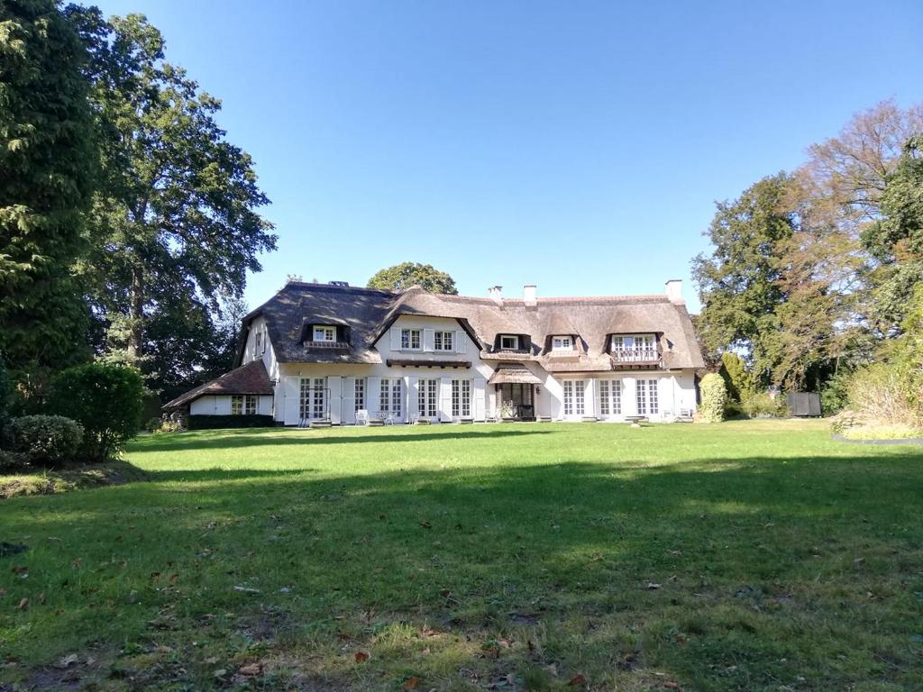 a large white house with a large grass field at Villa Monceau in Ottignies