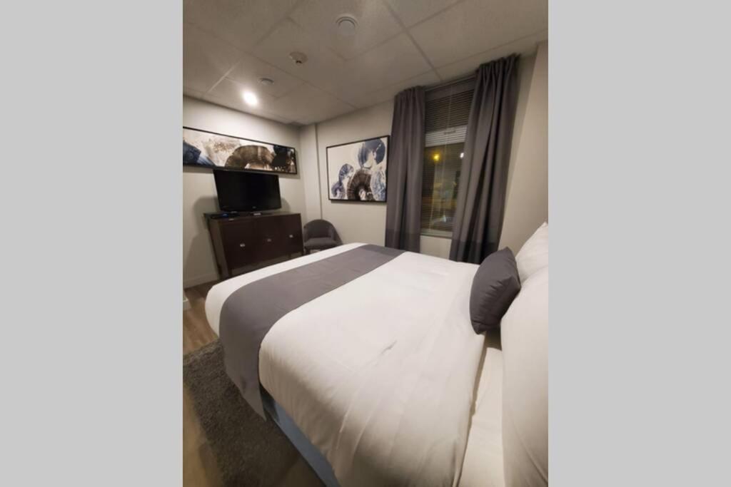 ein Hotelzimmer mit einem weißen Bett und einem Fenster in der Unterkunft Cozy Sweet Studio #4, Only 10 min to D.T. Ottawa in Gatineau