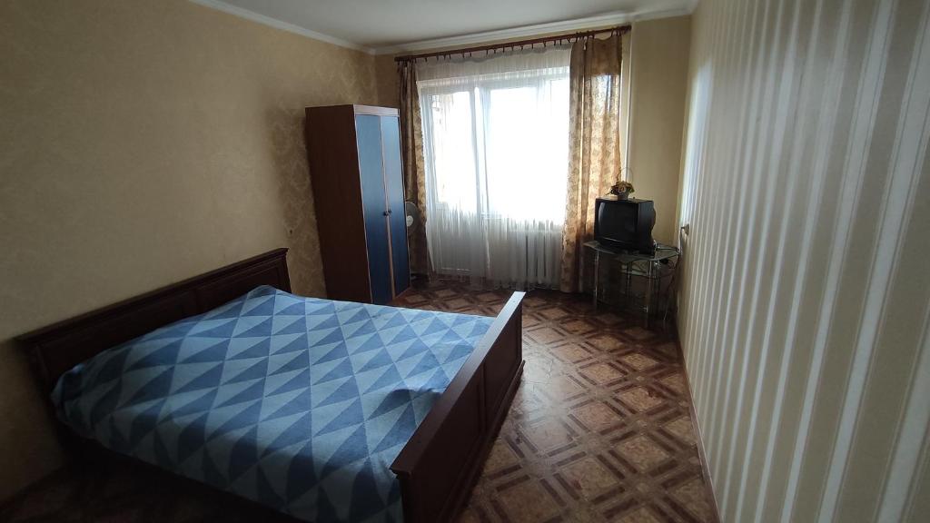 a bedroom with a blue bed and a window at 1-ная квартира по адресу Глушко 28 in Odesa