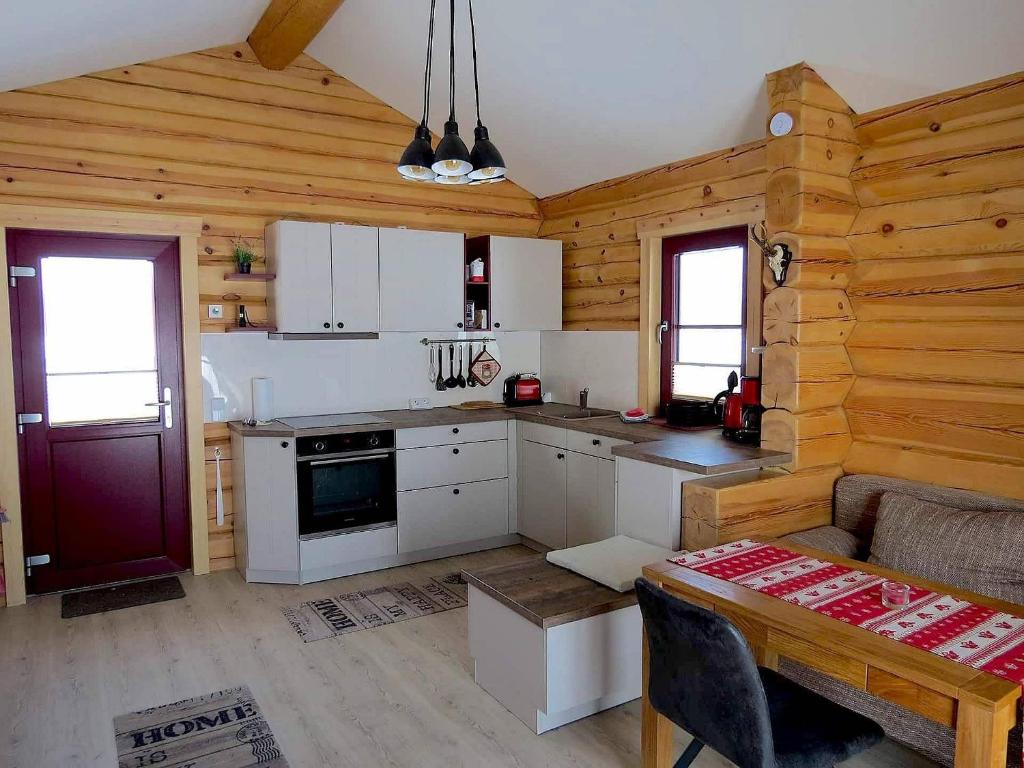 eine Küche mit weißen Schränken und einer Holzwand in der Unterkunft Traditionshof Lausitzer Teich- und Waldwirtschaft in Petershain