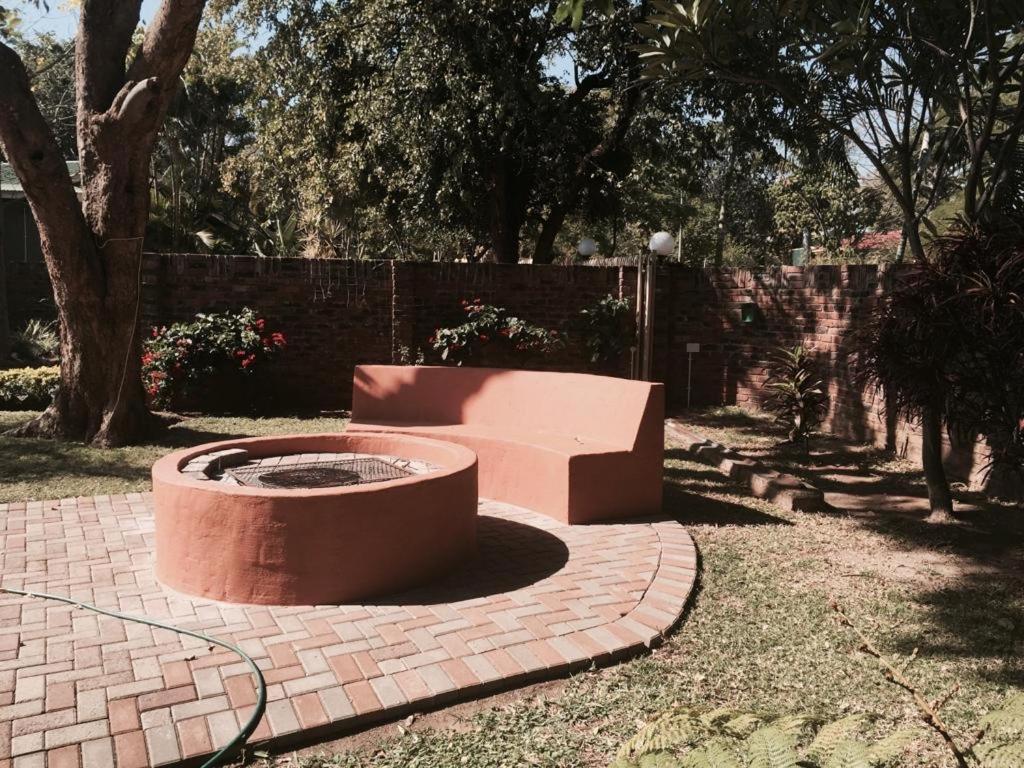 a fire pit in a yard with trees and a fence at Danamara Garden Studios in Phalaborwa