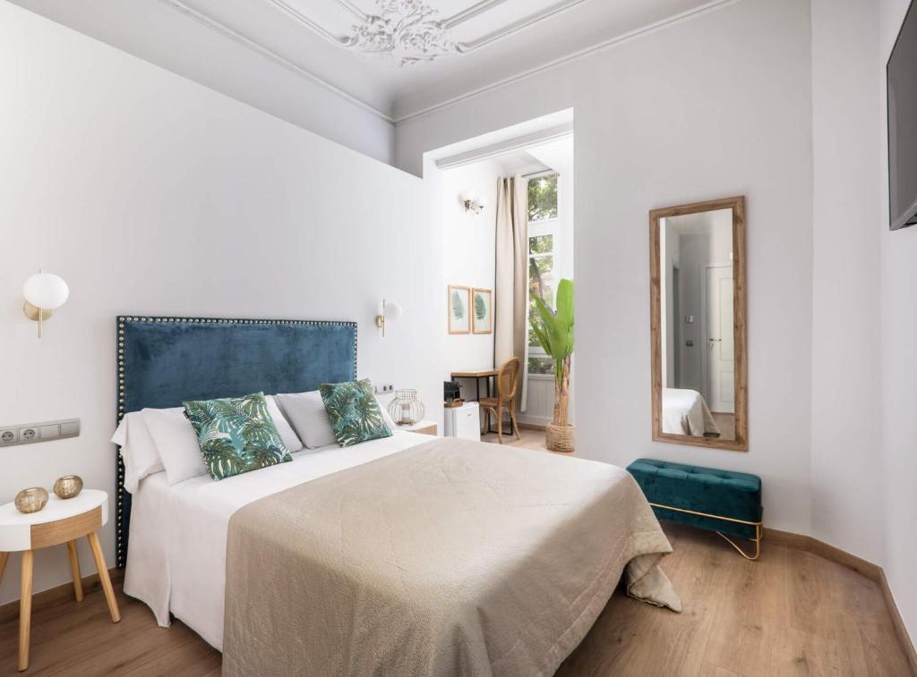 a white bedroom with a large bed and a mirror at La Maison de Barcelone in Barcelona